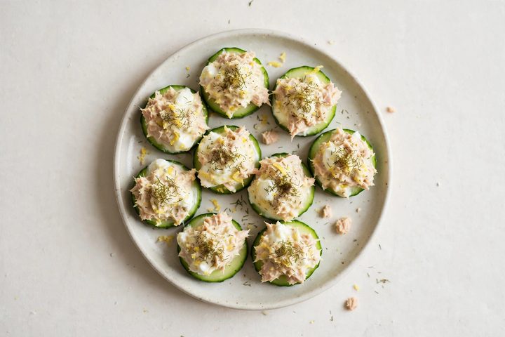 Overhead view of a plate of cucumber rounds topped with lemon tuna salad and dill